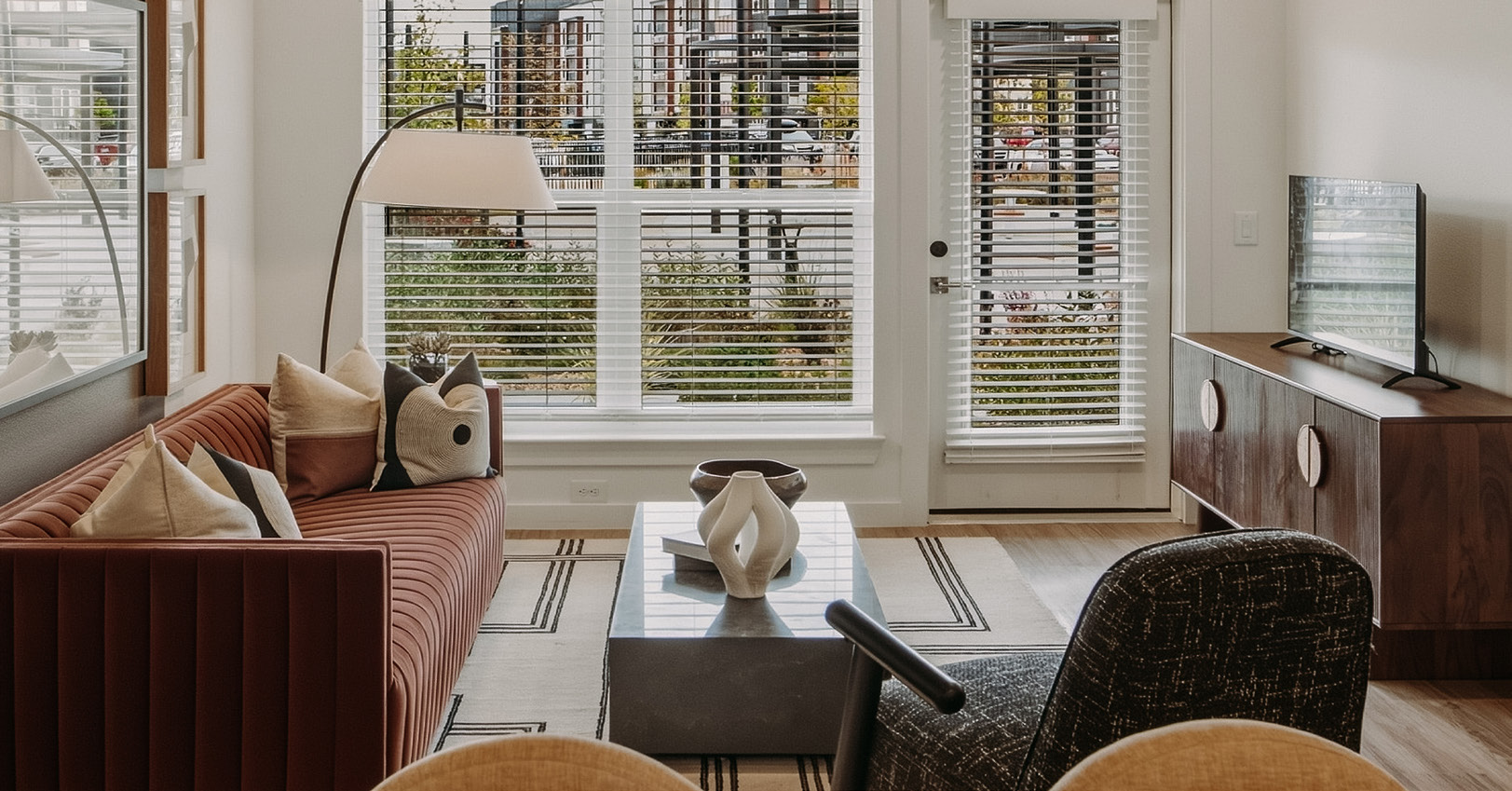 Apartment living room with a sofa, chairs and large windows