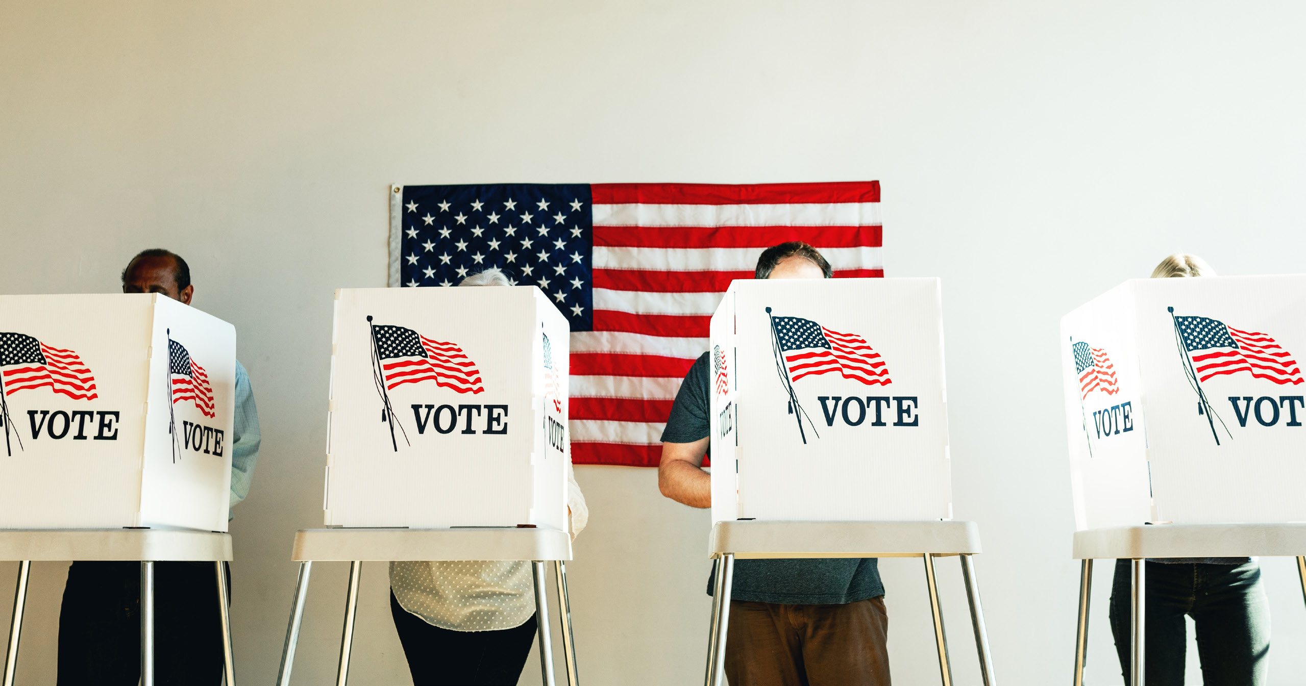 Voters at booths marked VOTE, with an American flag behind them