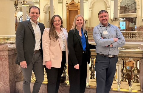 Four multifamily housing professionals standing together inside the Capitol.