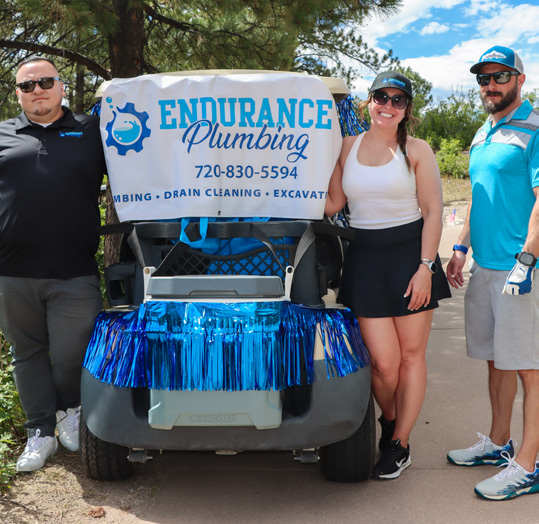 Endurance Plumbing representatives beside a decorated golf cart